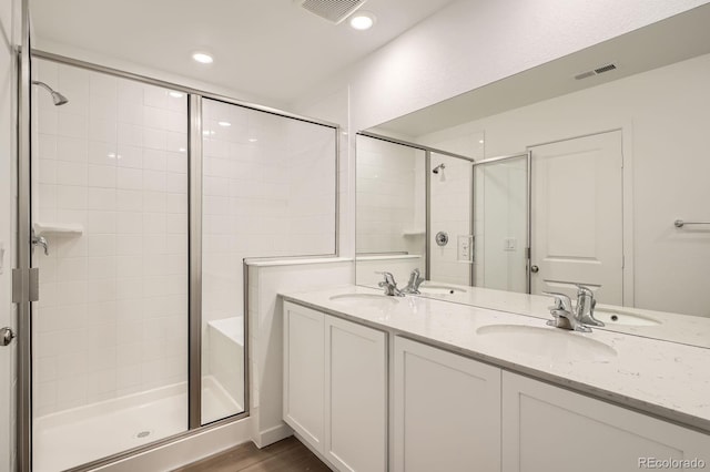 15228 Detroit St, Thornton, CO 80602 - bathroom featuring a shower stall, double vanity, wood finished floors, and recessed lighting