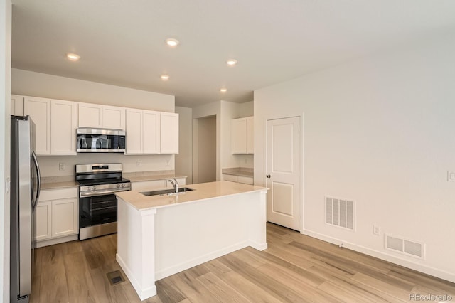 15228 Detroit St, Thornton, CO 80602 - kitchen with stainless steel appliances, light wood-type flooring, a center island with sink, white cabinetry, and recessed lighting