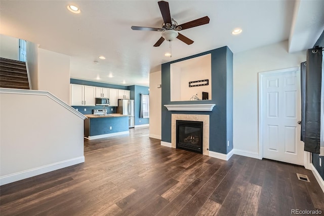 5624 Killdeer St, Brighton, CO 80601 - unfurnished living room with a ceiling fan, dark wood-style flooring, baseboards, recessed lighting, and a tiled fireplace