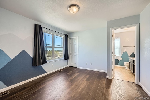 5624 Killdeer St, Brighton, CO 80601 - unfurnished bedroom with dark wood-style flooring, baseboards, a textured ceiling, and ensuite bathroom