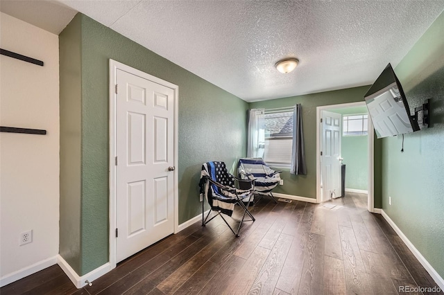 5624 Killdeer St, Brighton, CO 80601 - sitting room with dark wood-style floors, a textured wall, a textured ceiling, and baseboards