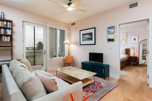 living room with light wood finished floors, visible vents, baseboards, and a ceiling fan