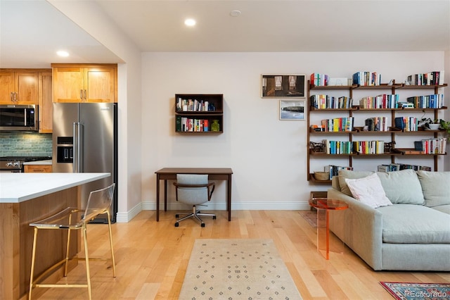 living area featuring recessed lighting, light wood-style floors, and baseboards