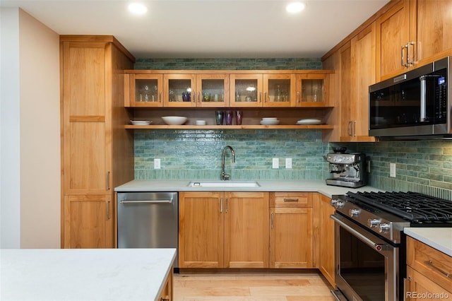 kitchen featuring decorative backsplash, stainless steel appliances, light countertops, and a sink