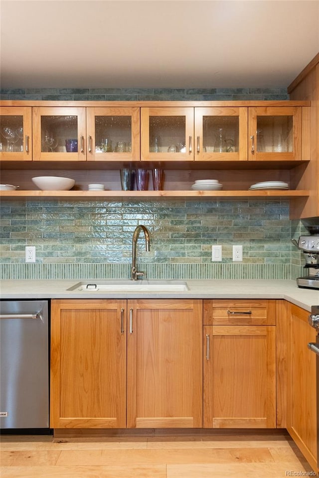 bar featuring a sink, light wood finished floors, decorative backsplash, range, and dishwasher