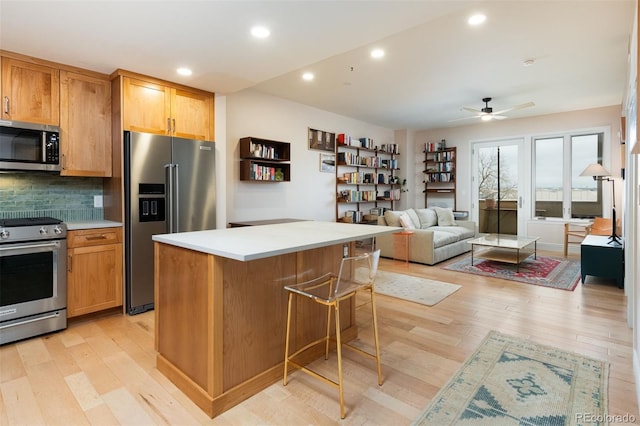 kitchen with backsplash, appliances with stainless steel finishes, light wood-style flooring, and light countertops