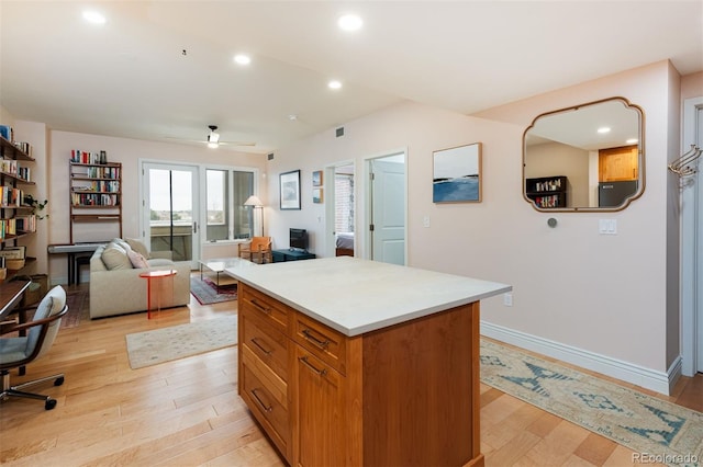 kitchen featuring light wood finished floors, a kitchen island, recessed lighting, light countertops, and baseboards