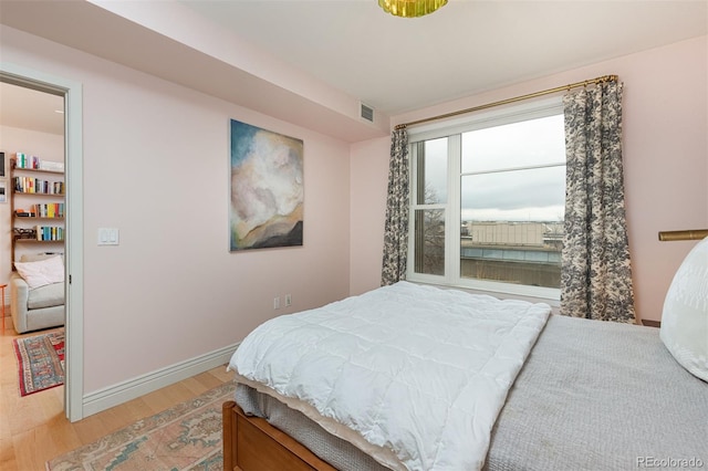 bedroom featuring light wood-type flooring, baseboards, and visible vents