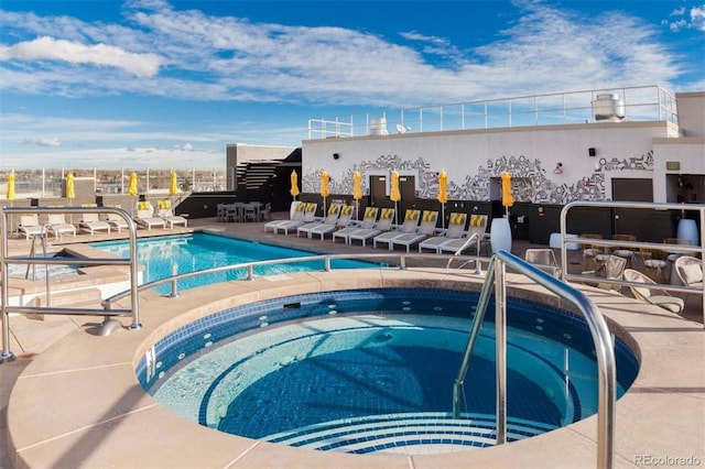 pool with a patio area and a community hot tub