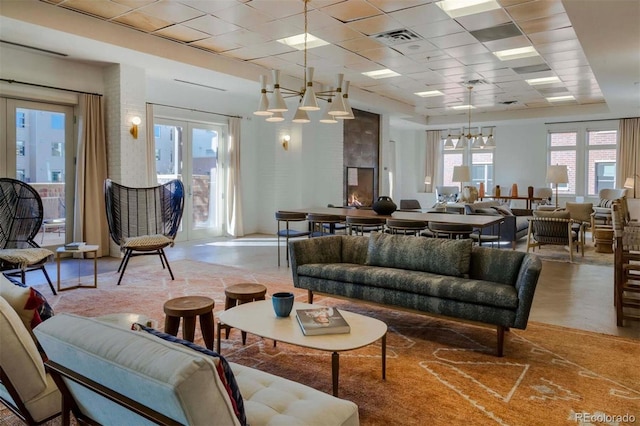 living area featuring a wealth of natural light, visible vents, a notable chandelier, and a drop ceiling