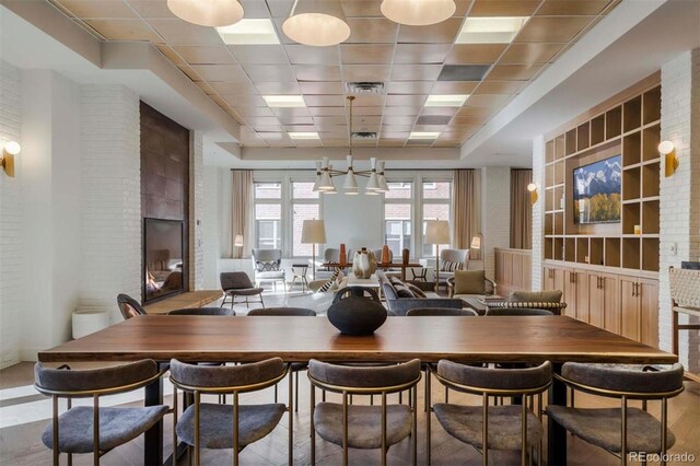 dining area with a drop ceiling, a brick fireplace, and visible vents