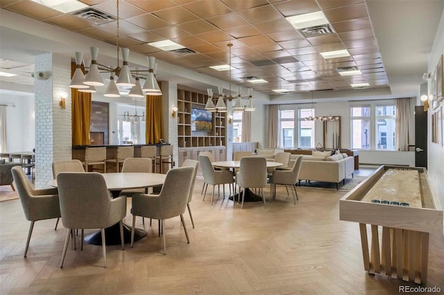 dining space with an inviting chandelier, a paneled ceiling, and visible vents