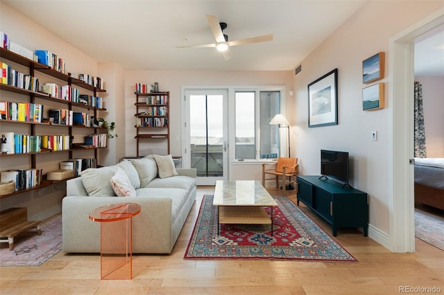 living room featuring light wood-style flooring, baseboards, visible vents, and ceiling fan