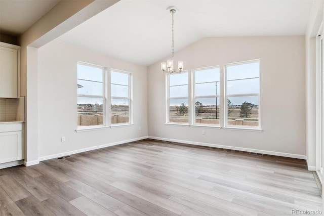 unfurnished dining area with vaulted ceiling, light wood-type flooring, and an inviting chandelier