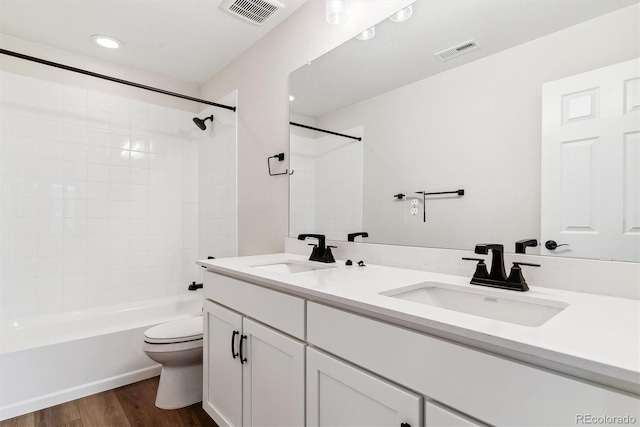 full bathroom featuring hardwood / wood-style floors, vanity, toilet, and tiled shower / bath