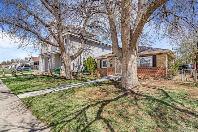 view of front of property featuring brick siding, fence, and a front yard