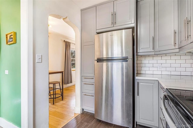 kitchen with backsplash, gray cabinetry, appliances with stainless steel finishes, and dark wood-type flooring