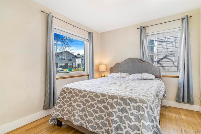 bedroom featuring baseboards, light wood-style flooring, and multiple windows