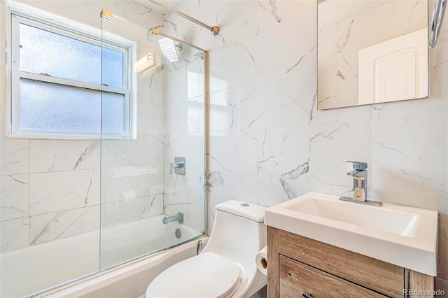 full bath featuring tile walls, vanity, toilet, and shower / bath combination with glass door