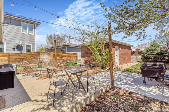 view of patio with outdoor dining area, a fenced backyard, an outbuilding, and a deck