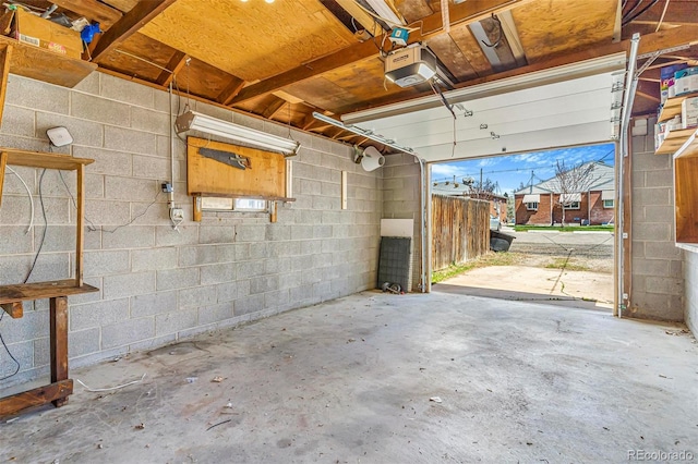 garage featuring concrete block wall and a garage door opener
