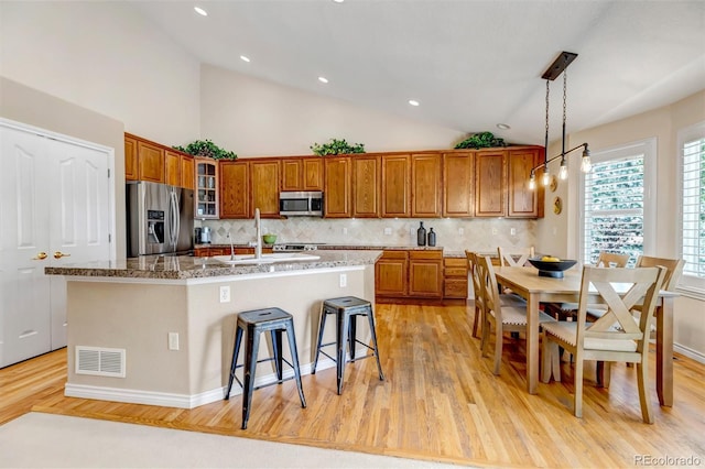 6633 E 166th Pl, Brighton, CO 80602 - kitchen featuring appliances with stainless steel finishes, brown cabinets, light wood finished floors, tasteful backsplash, and recessed lighting