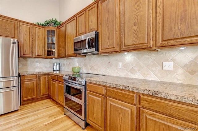 6633 E 166th Pl, Brighton, CO 80602 - kitchen with stainless steel appliances, brown cabinetry, tile counters, and glass insert cabinets