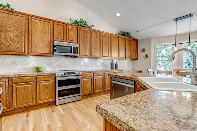 6633 E 166th Pl, Brighton, CO 80602 - kitchen with appliances with stainless steel finishes, a sink, brown cabinets, tile countertops, and vaulted ceiling