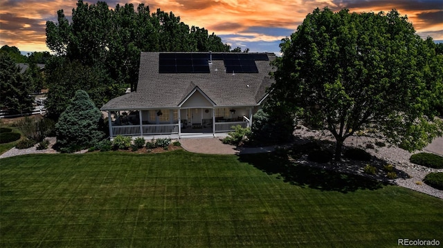6633 E 166th Pl, Brighton, CO 80602 - view of front facade with covered porch, a lawn, roof mounted solar panels, and a shingled roof