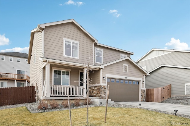 traditional home with fence, covered porch, concrete driveway, an attached garage, and a front yard