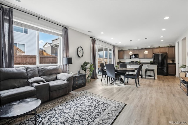 living area with a wealth of natural light, recessed lighting, and light wood finished floors