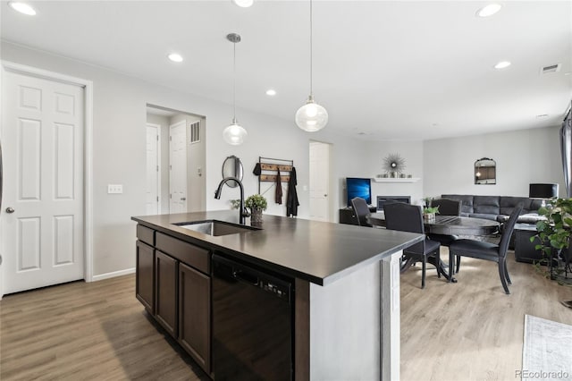 kitchen featuring dark countertops, light wood-style flooring, dishwasher, and a sink