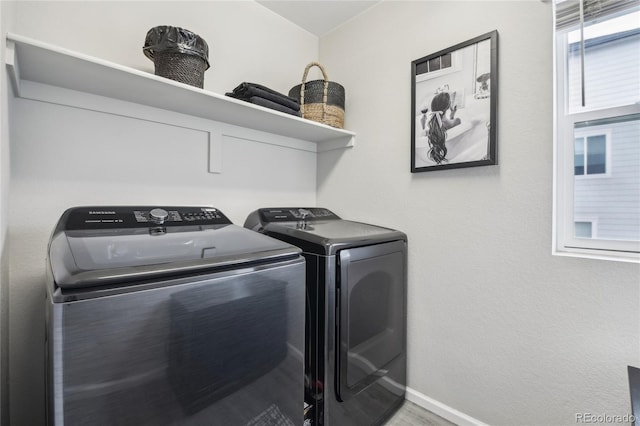 clothes washing area featuring laundry area, washing machine and dryer, and baseboards