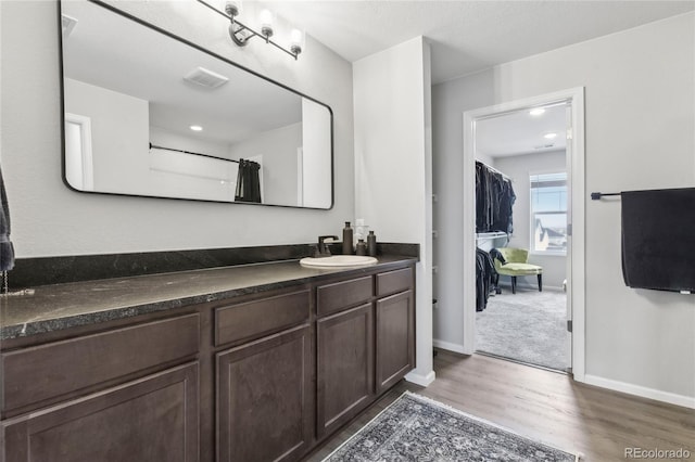 full bathroom featuring vanity, wood finished floors, visible vents, and baseboards