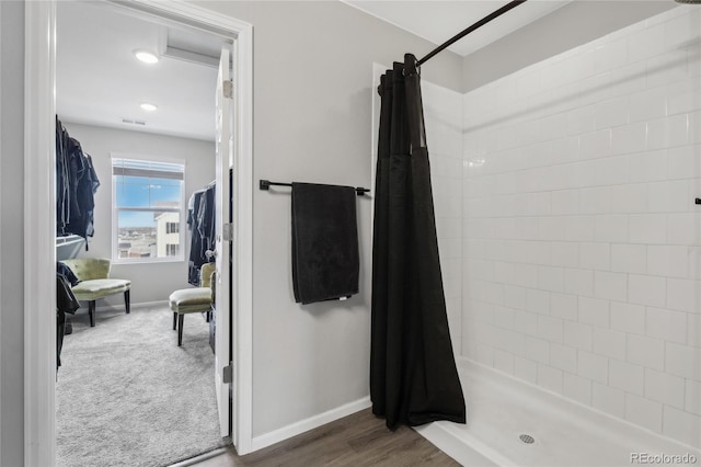 bathroom featuring wood finished floors, baseboards, a stall shower, and visible vents