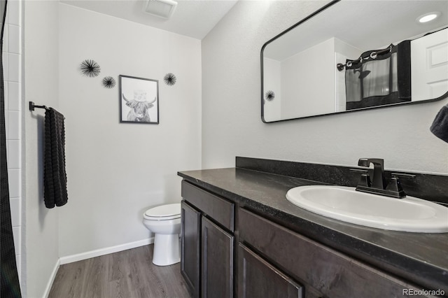 full bath featuring visible vents, toilet, wood finished floors, baseboards, and vanity