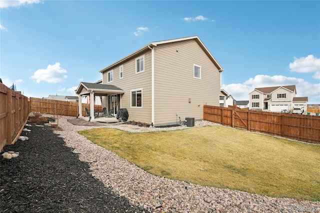 rear view of property with a yard, central AC unit, a fenced backyard, and a patio area