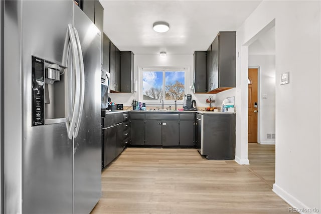 kitchen with stainless steel fridge, sink, and light wood-type flooring