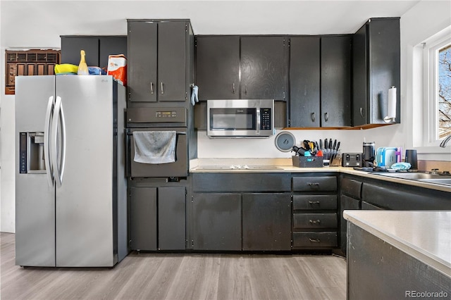 kitchen with sink, light hardwood / wood-style flooring, and black appliances