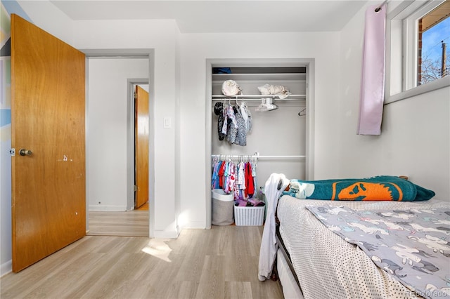 bedroom with light hardwood / wood-style floors and a closet