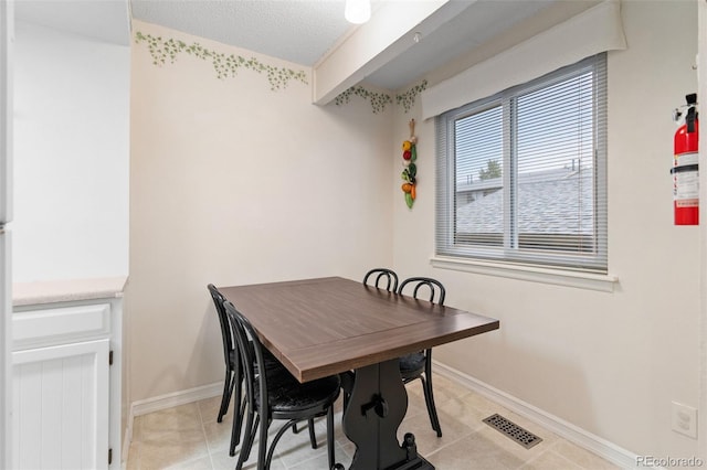 dining space with a textured ceiling and light tile patterned floors