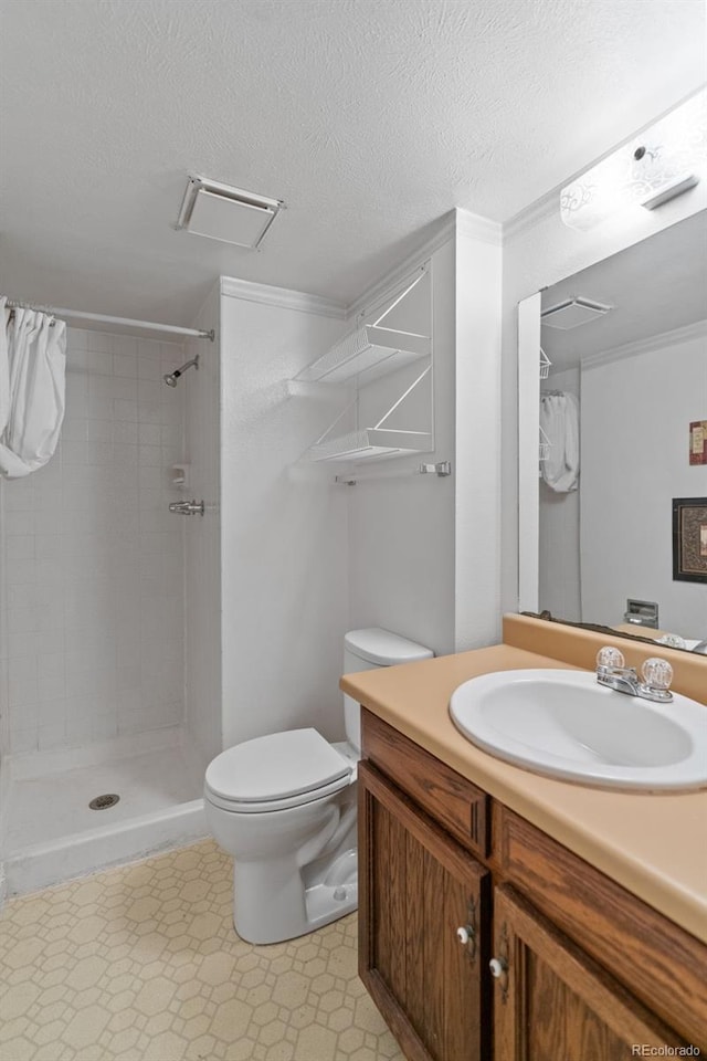 bathroom with vanity, a tile shower, a textured ceiling, and toilet