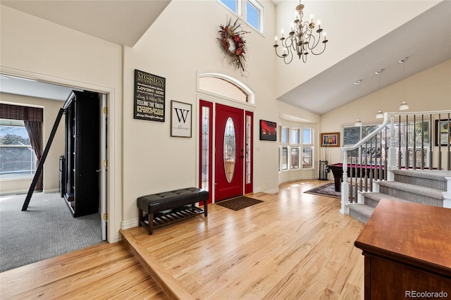 entryway featuring stairs, a notable chandelier, light wood-type flooring, and a wealth of natural light