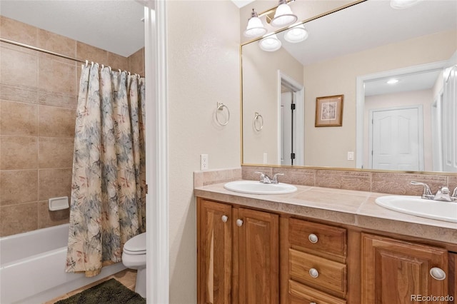 bathroom featuring double vanity, toilet, and a sink