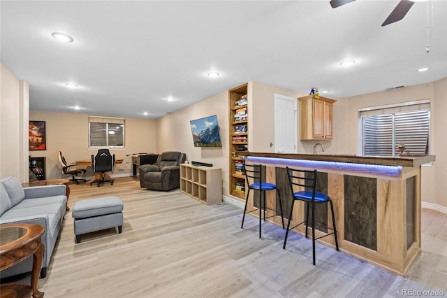 living room featuring indoor wet bar, recessed lighting, and light wood-style floors