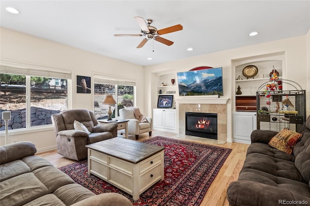 living room featuring recessed lighting, built in shelves, a fireplace, and light wood-style floors