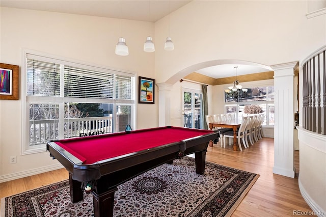 playroom with arched walkways, plenty of natural light, and light wood-style flooring