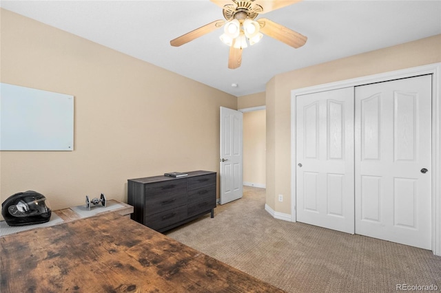 bedroom with light carpet, baseboards, a ceiling fan, and a closet