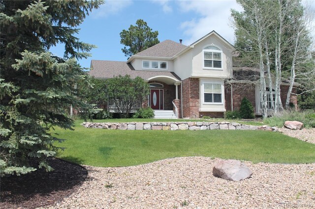 8389 Owl Roost Ct, Parker, CO 80134 - view of front of property with brick siding, a front yard, stucco siding, and roof with shingles