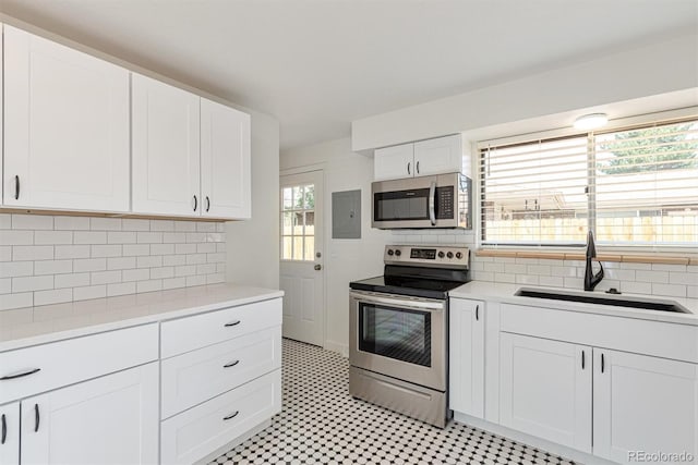 1331 Xanadu St, Aurora, CO 80011 - kitchen with stainless steel appliances, light countertops, white cabinets, and decorative backsplash